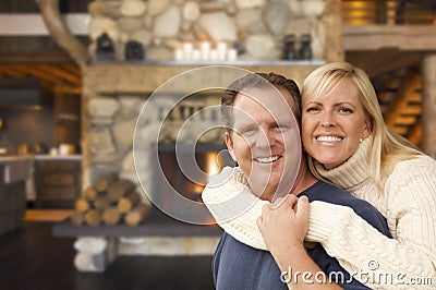 Affectionate Couple at Rustic Fireplace in Log Cabin Stock Photo