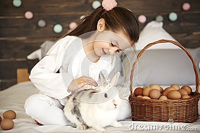 Affectionate girl stroking her rabbit in bed Stock Photo