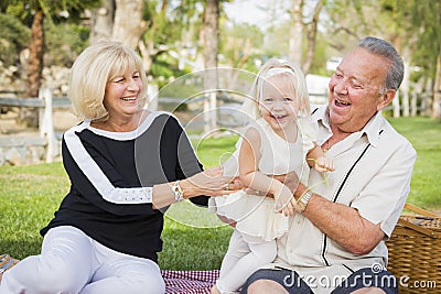 Affectionate Granddaughter and Grandparents Playing At The Park Stock Photo