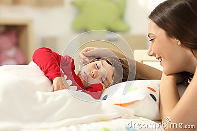Affectionate mother looking at her toddler sleeping Stock Photo