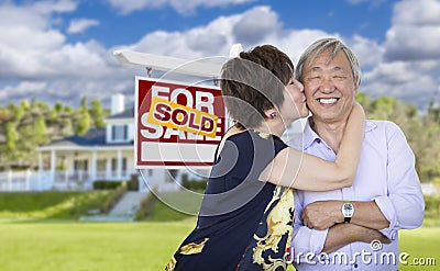 Affectionate Senior Chinese Couple In Front of House and Sign Stock Photo