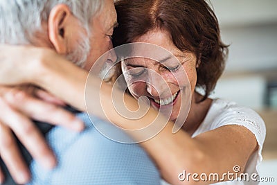 Affectionate senior couple in love standing indoors at home, hugging. Stock Photo