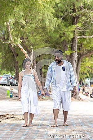 Afircan American Black man hold hand Asia Woman lover honeymoon time on sea beach - outdoor summer beach concept Stock Photo