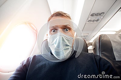 Afraid of fear flying on airplane and height tourist man in safe medical mask. Concept aerophobia or aviophobia Stock Photo