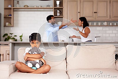 Afraid little girl holding a teddy in an abusive household. Young couple fighting while their child sits on the couch Stock Photo