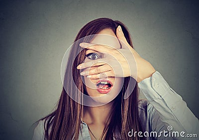 Afraid woman peeking through her fingers Stock Photo