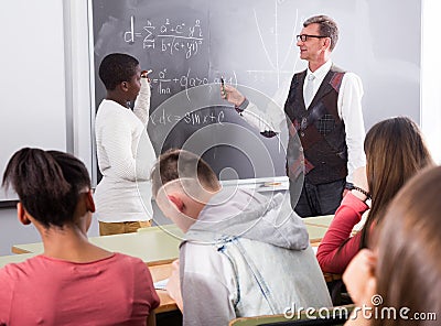 Aframerican student answers near blackboard at math lesson Stock Photo