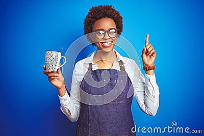 African american barista woman wearing bartender uniform holding cup over blue background surprised with an idea or question Stock Photo