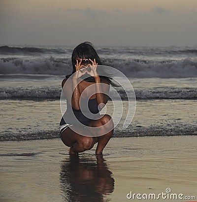 African american black woman walking on sunset beach enjoying water and sand doing heart shape with hands Stock Photo