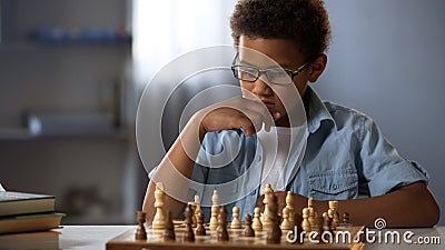 African American boy logically thinking out strategy of playing chess, hobby Stock Photo