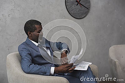 African american Businessman reading newspaper and checking time Stock Photo