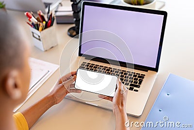 African american businesswoman in casual using smartphone in front of laptop with copy space Stock Photo