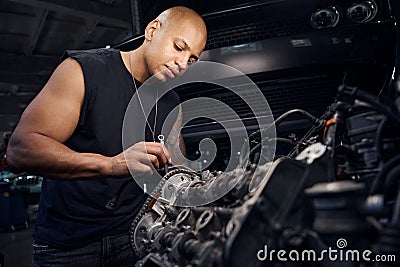 African-American car maintenance station worker repairing some details in engine Stock Photo