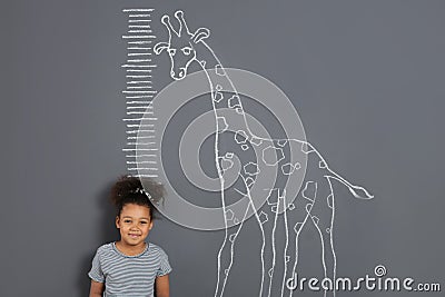 African-American child measuring height near chalk giraffe drawing Stock Photo