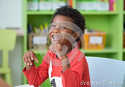 African American ethnicity kid smiling at library in kindergarten preschool classroom.happy emotion.education concept. Stock Photo