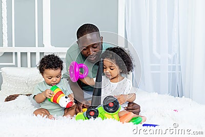 African-American family dad with kids babies play and collect a colorful pyramid at home on the bed, happy family Stock Photo