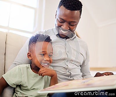 African american father bonding with his at home. Black male helping his son read a book and practice learning while Stock Photo