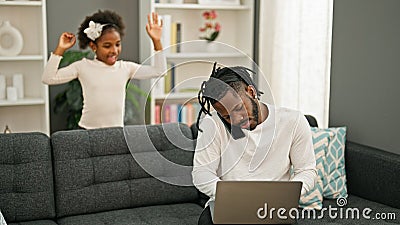 African american father and daughter sitting on sofa working while child disturb at home Stock Photo