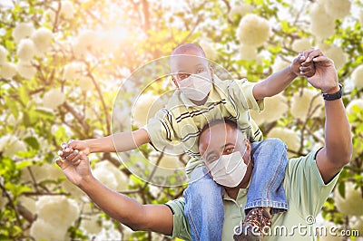 African American Father And Son Playing Outdoors Wearing Medical Face Mask Stock Photo