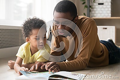 African American father and toddler son reading book together Stock Photo