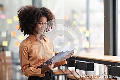 African American female employee write down on colorful sticky notes manage list, concentrated biracial woman work on Stock Photo