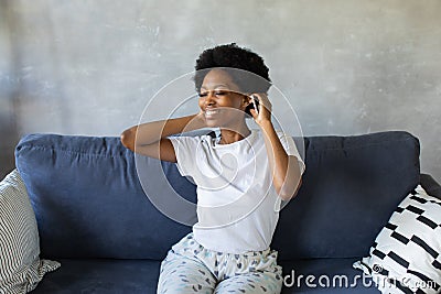 African American girl dancing with her phone on the couch in a cozy room Stock Photo