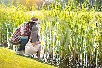 african american granddaughter and her grandfather sitting near lake Stock Photo