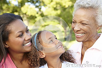 African American Grandmother, Mother And Daughter Relaxing In Park Stock Photo