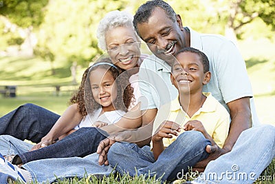 African American Grandparents With Grandchildren Relaxing In Park Stock Photo