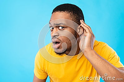 African American Guy Listening Holding Hand Near Ear, Blue Background Stock Photo