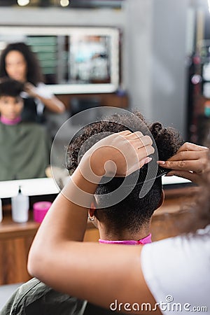 African american hairstylist combing hair of Stock Photo