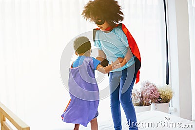 African American happy and confident young kids playing and dressing up as superhero together in bedroom Stock Photo