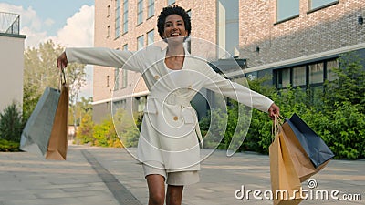 African American happy woman walking in city from boutique store shop spinning dancing shopper girl female buyer going Stock Photo