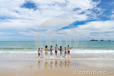 African American kid holding hand together running into the sea on the seashore of a tropical island Stock Photo