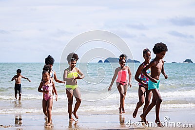 African American, Kids group in swimwear enjoying running to play the waves on beach. Ethnically diverse concept. Having fun after Stock Photo