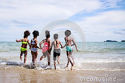 African American, Kids group in swimwear enjoying running to play the waves on beach. Ethnically diverse concept. Having fun after Stock Photo
