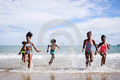 African American, Kids group in swimwear enjoying running to play the waves on beach. Ethnically diverse concept. Having fun after Stock Photo