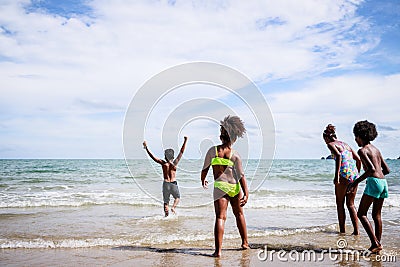 African American, Kids group in swimwear enjoying running to play the waves on beach. Ethnically diverse concept. Having fun after Stock Photo