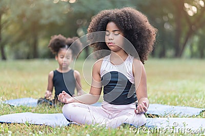 African American little girl sitting on the roll mat practicing meditate yoga in the park outdoor Stock Photo