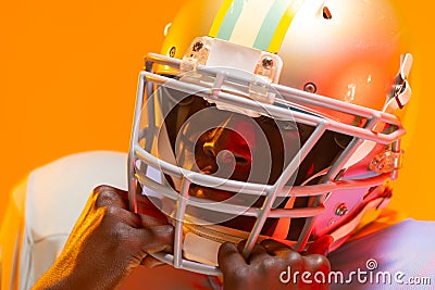 African american male american football player wearing helmet with neon orange lighting Stock Photo