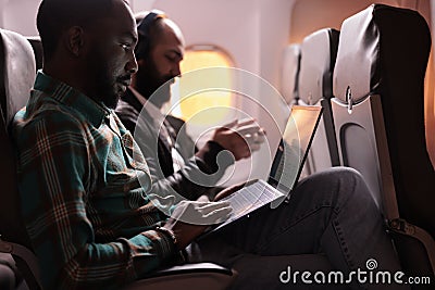 African american male freelancer working on laptop during sunset flight Stock Photo