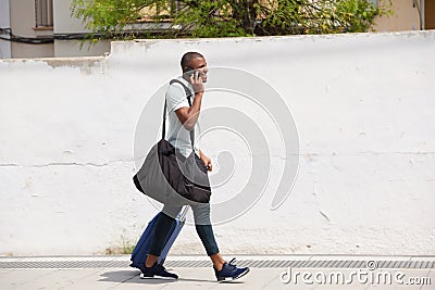 African american male traveler walking outside and talking on cell phone Stock Photo