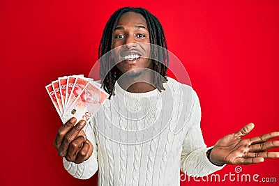 African american man with braids holding 20 israel shekels banknotes celebrating achievement with happy smile and winner Stock Photo