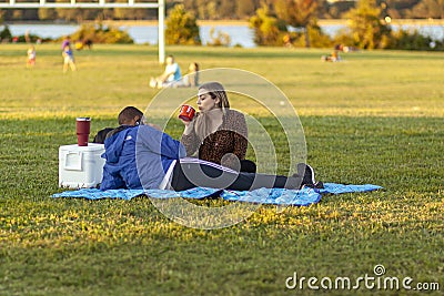 An African American man and a caucasian woman are relaxing in Gravelly Point park at a sunny afternoon. Editorial Stock Photo