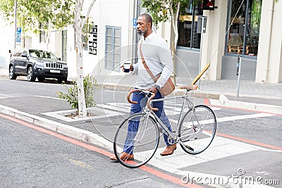 African American man crossing the street and holding his bike Stock Photo