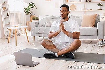 African American Man Doing Yoga Sitting At Laptop At Home Stock Photo