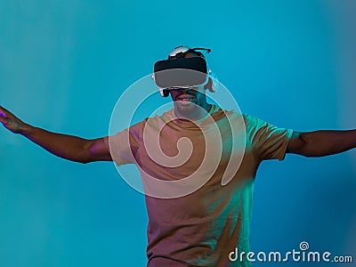 African American man dons VR glasses, engrossed in a virtual reality simulation, gesturing with hands, against a Stock Photo