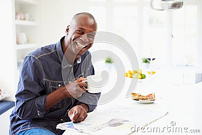 African American Man Eating Breakfast And Reading Newspaper Stock Photo