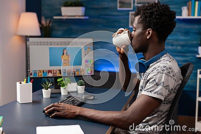 African american man editor drinking coffee while doing photo retouch Stock Photo