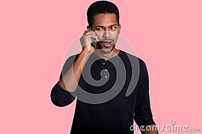 African American man has telephone coversation, hears something unpleasant news, looks aside, wears black outfit. Handsome dark Stock Photo